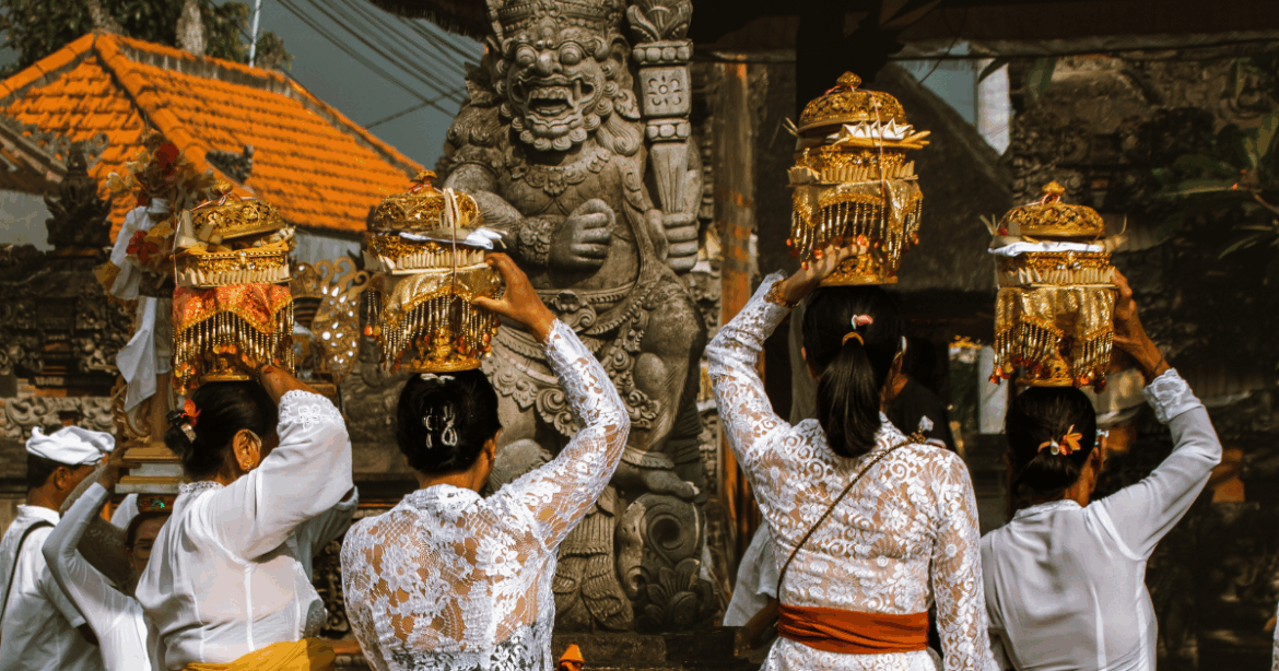 Mulheres balinesas em trajes tradicionais carregando oferendas durante festival em templo em Bali